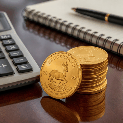 Gold Krugerrand coins beside a calculator, illustrating premium over spot when buying physical gold